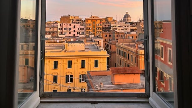 A cityscape through a window with a clear sky and buildings. - Your window overlooking St. Peter's (Roma)