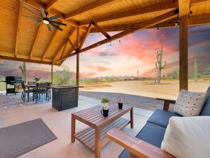 A covered outdoor seating area with a wooden table, chairs, and a sofa. - Boulder Apache Junction (Apache Junction)