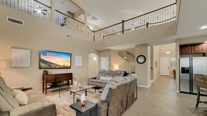 A spacious living room with a large sectional sofa, a flat-screen TV, and a staircase leading to an upper level. - Cline Maricopa (Maricopa)