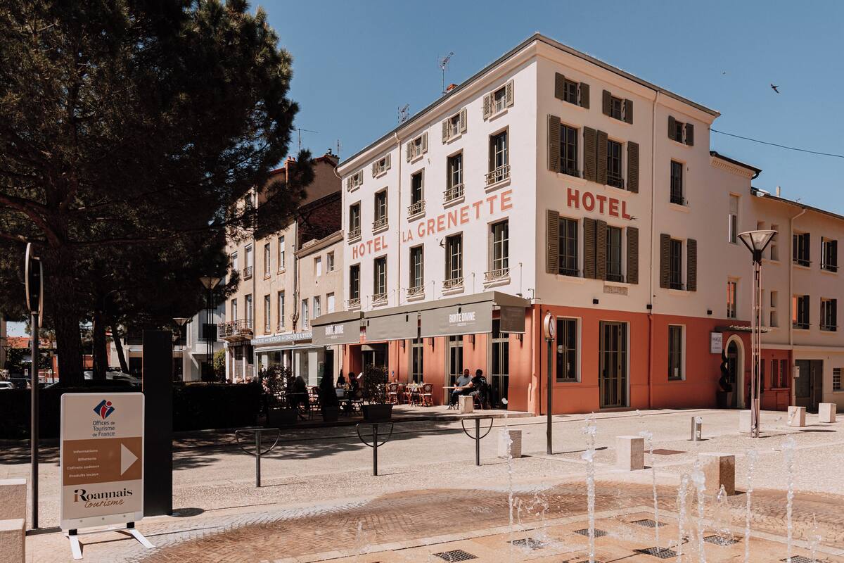A hotel with a sign reading "HOTEL LA GRENETTE" and a signboard for "Offices de Tourisme de France" in front.