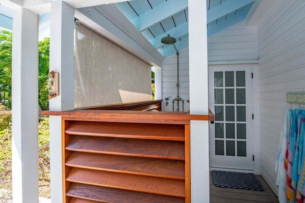A covered outdoor area with a wooden bench, a door with frosted glass panels, and a ceiling fan.