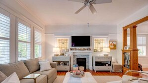 Ein Wohnzimmer mit Kamin, Fernseher und Deckenventilator.