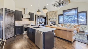 A modern kitchen with a central island, dark cabinetry, and a stone accent wall. - River Run Rendezvous (Keystone)