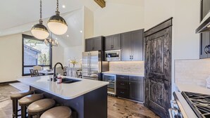 A modern kitchen with a central island, stainless steel appliances, and dark cabinetry. - River Run Rendezvous (Keystone)