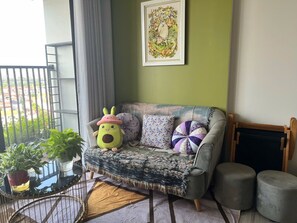 A cozy living area with a sofa, cushions, a small table with plants, and a framed picture on the wall.