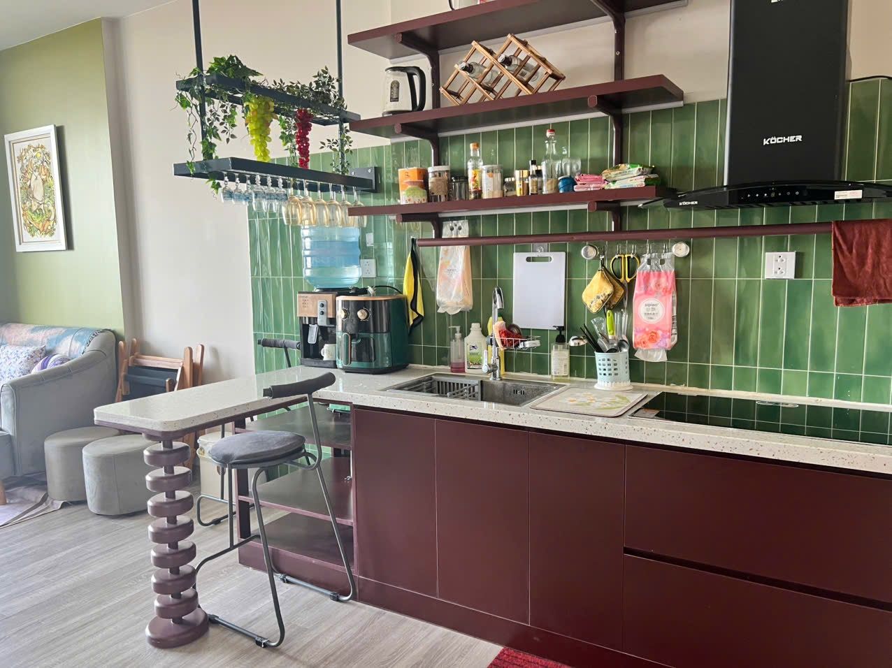 A modern kitchen with a bar area, green tiled backsplash, and a hanging plant.