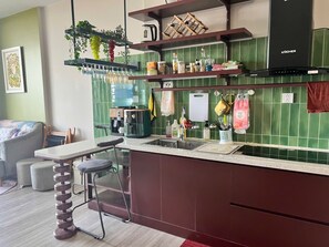 Une cuisine moderne avec un coin bar, un dosseret de carrelage vert et une plante suspendue.