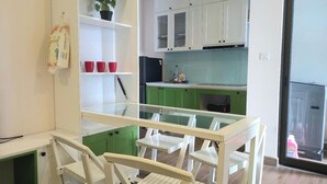 A kitchen with white cabinets, a green countertop, and a glass dining table with chairs.