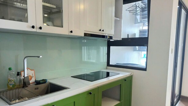 A kitchen with a sink, a stove, and green cabinets.