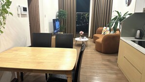 Un saló modern amb taula de menjador, dos sofàs, televisió i zona de cuina.