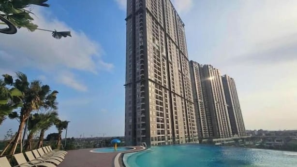 Un edifici residencial alt amb piscina i palmeres.