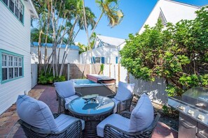 A patio area with wicker furniture and a grill. - Southernmost Retreat | On Duval! With Hot Tub, Patio (Key West)