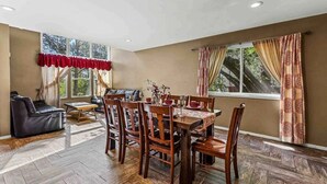 A dining area with a wooden table and chairs, a sofa, and a window with curtains. - Fanning Flagstaff (Flagstaff)