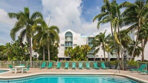 Un hôtel doté d’une piscine, entouré de palmiers et offrant une vue sur un ciel dégagé.