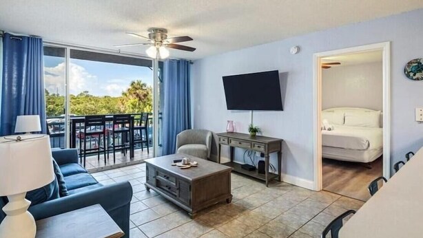 Un salon moderne comprenant un canapé, une table basse, un téléviseur et un balcon avec un espace salon extérieur.