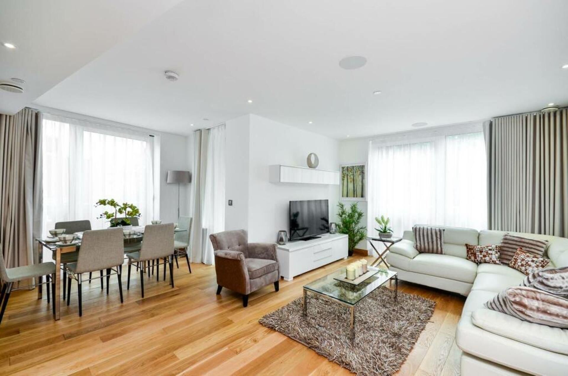 A modern living room with a dining area, a sofa, a coffee table, and a TV.