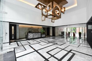 A spacious lobby with a geometric marble floor, a reception desk, and a modern chandelier. - Charming 3 Bedroom Apartment in Central London (London)