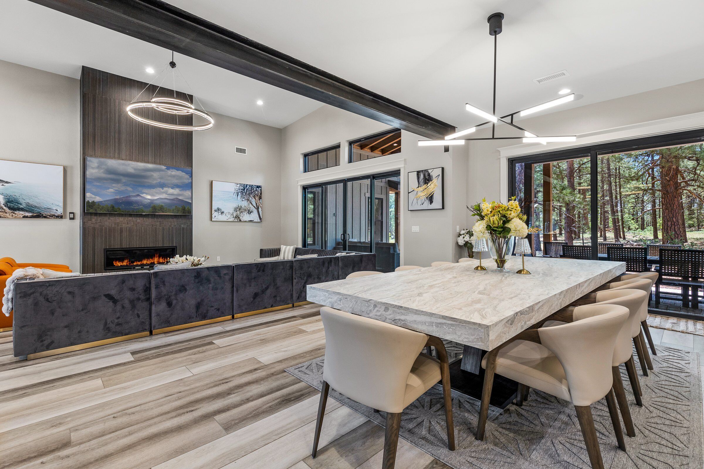 A modern dining area with a marble table, beige chairs, and a black sofa.