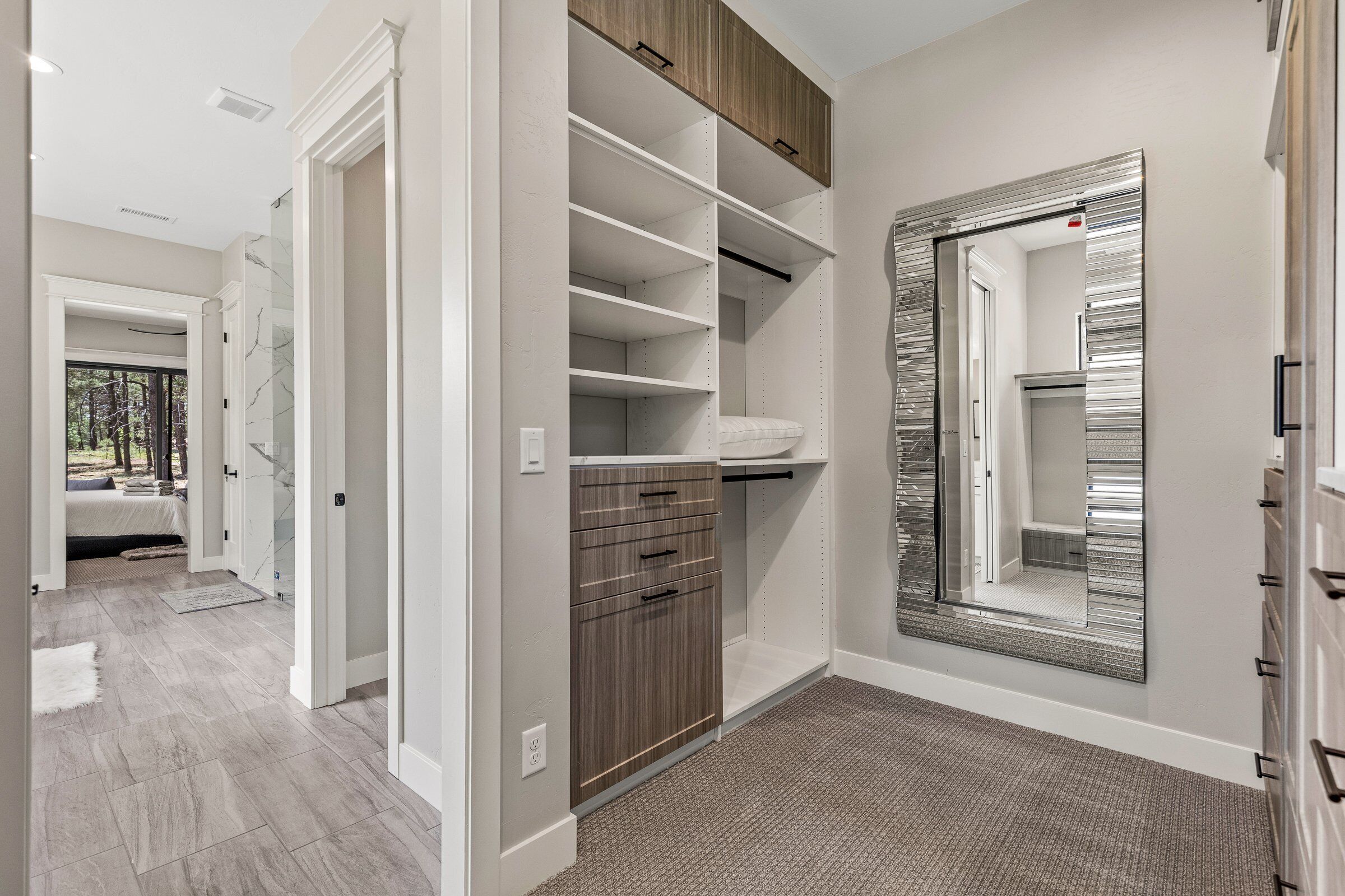 Un dressing accessible sans porte, doté d’étagères ouvertes, d’une porte-miroir et d’un banc intégré.