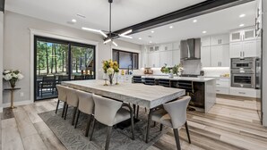 Una cocina moderna con una isla grande, muebles blancos y vistas al exterior.