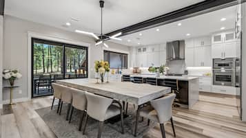 A modern kitchen with a large island, white cabinetry, and a view of the outdoors.