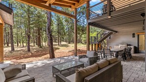 Un patio al aire libre con mobiliario de mimbre, una mesa de vidrio y zona de barbacoa.