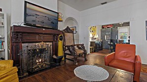 A living room with a fireplace, a television, and a dining area with a table and chairs. - Charming Ybor City Bungalow with Private Pool Oasis (Tampa)