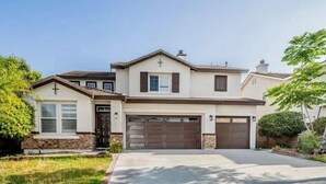Une maison à deux étages avec un garage, un porche à l’avant et une croix sur le toit.