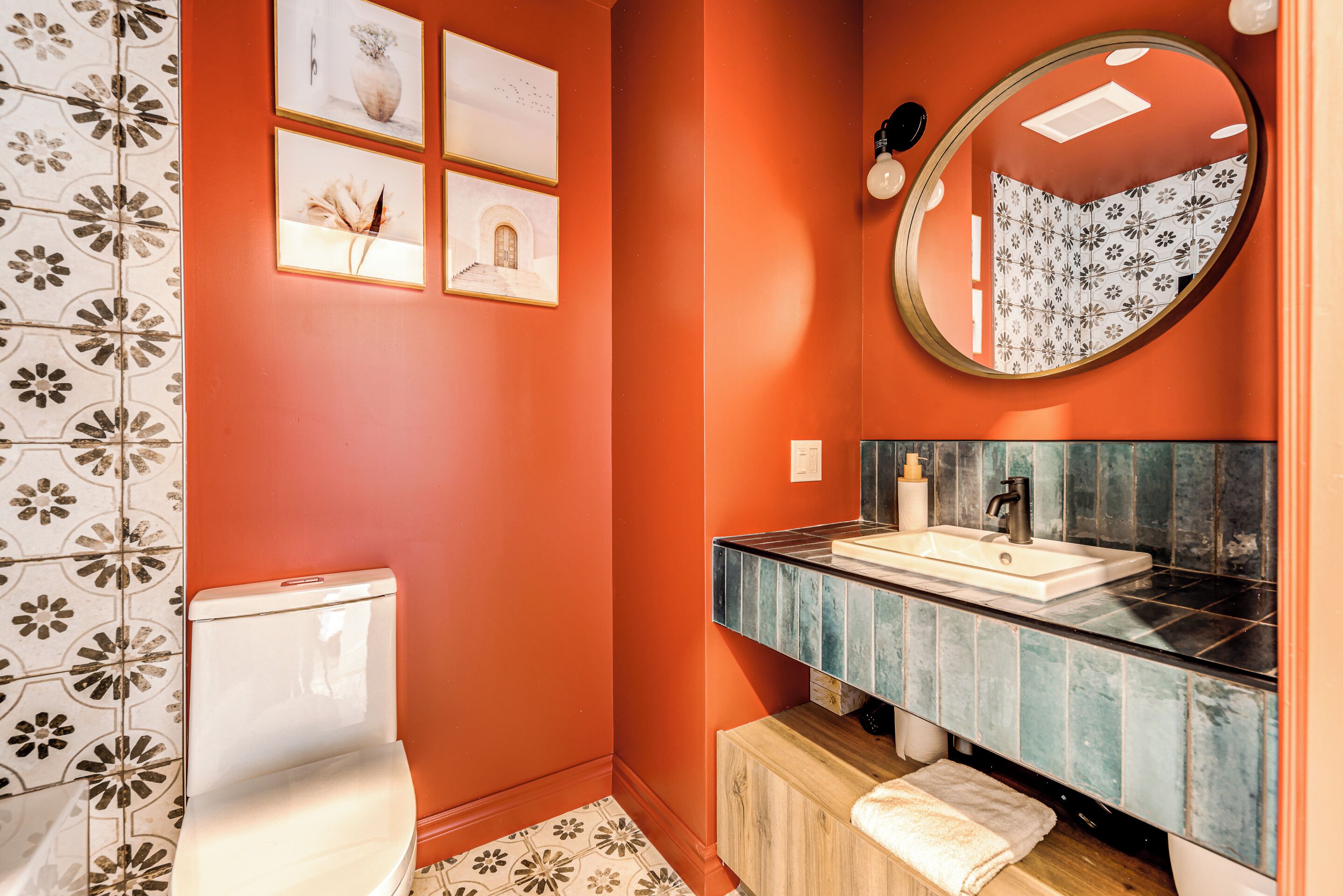 A bathroom with a toilet, a sink with a mirror, and a patterned shower curtain.