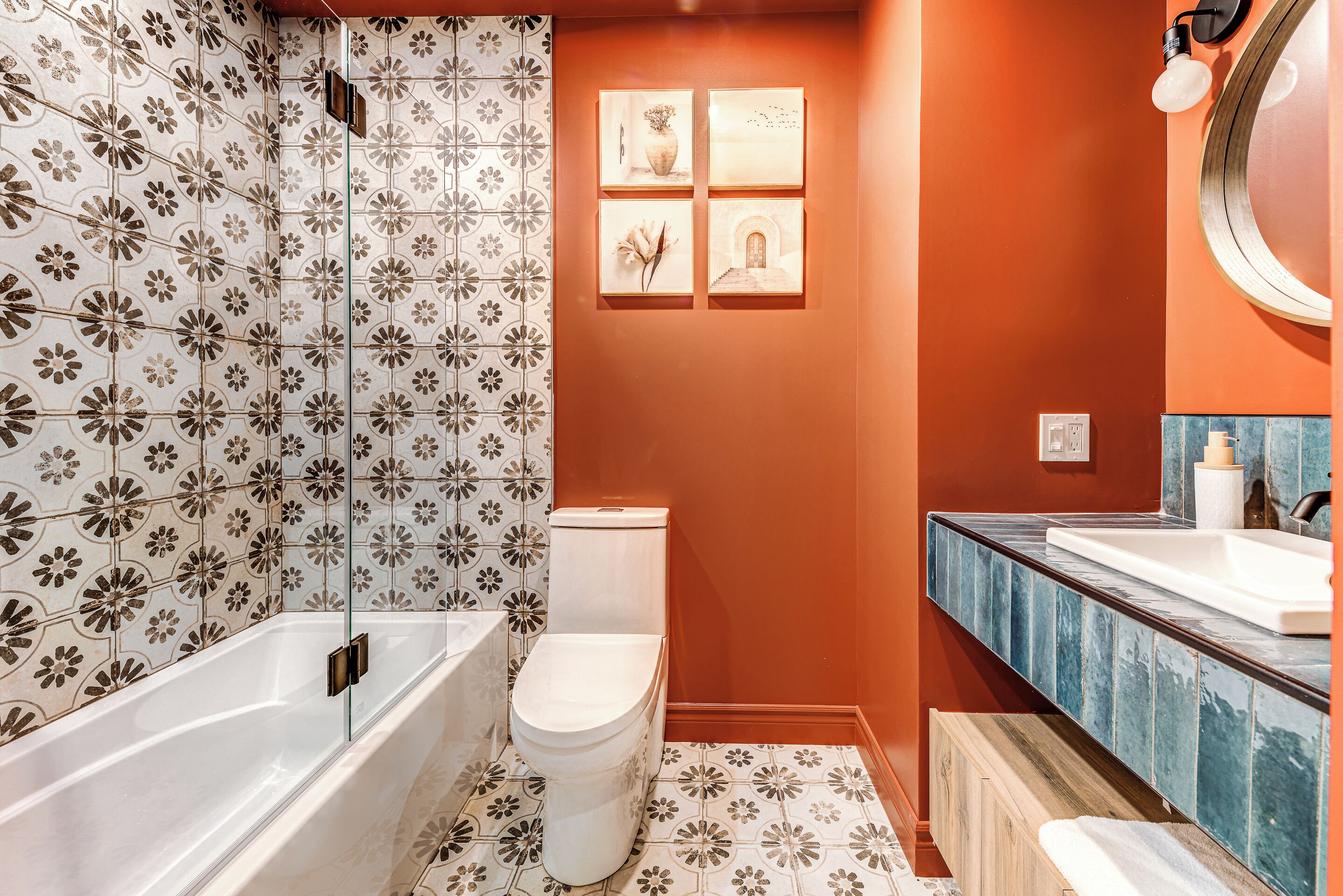 Ein Badezimmer mit Badewanne, Toilette und Waschbecken. Die Wände und der Boden sind mit floralem Muster gefliest.