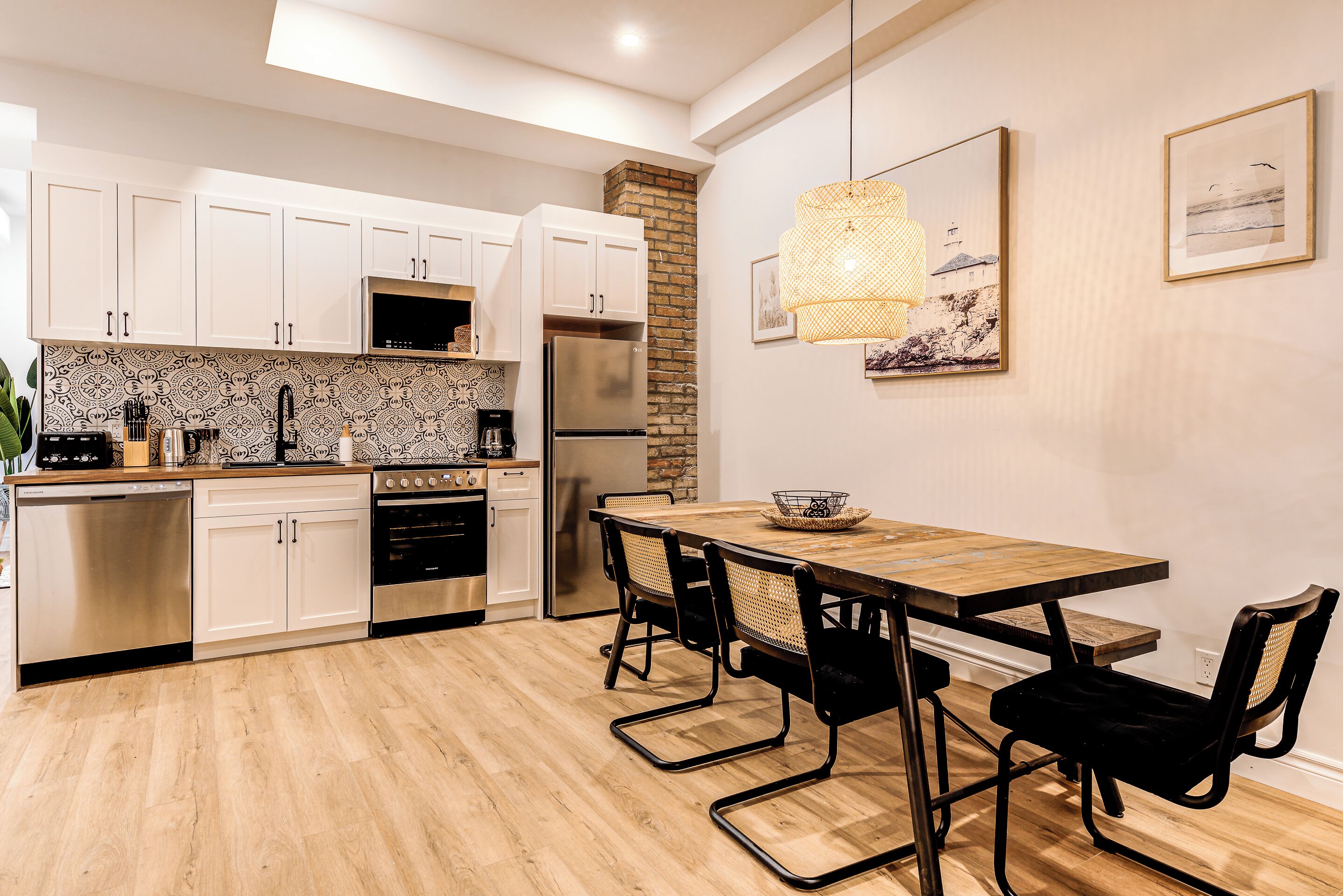 A modern kitchen with white cabinets, stainless steel appliances, and a wooden dining table with black chairs.