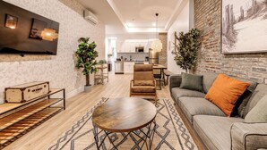 A modern living room with a sofa, a coffee table, and a TV mounted on the wall. - Bohemian Vieux Quebec Two Bedroom (Québec City)