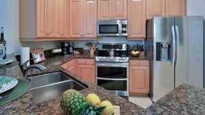 A kitchen with wooden cabinets, a stainless steel refrigerator, a microwave, an oven, and a sink. - Hammock Beach 2BD, 2BR Villa - Walk to the Ocean! (Palm Coast)