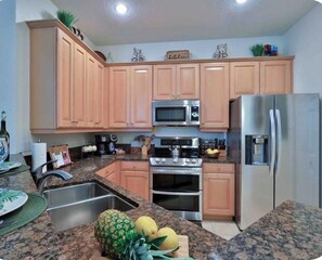 A kitchen with wooden cabinets, a stainless steel refrigerator, a microwave, an oven, and a sink. - Hammock Beach 2BD, 2BR Villa - Walk to the Ocean! (Palm Coast)
