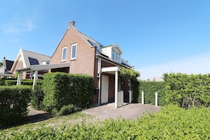 A two-story house with a brick facade, a pitched roof, and a small porch with a door. - Bungalow by Water Near Rotterdam (Simonshaven)