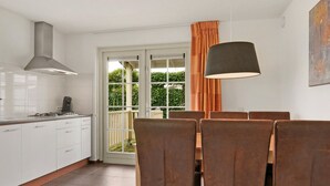 A modern kitchen with white cabinets, a gas stove, and a stainless steel range hood. - Bungalow by Water Near Rotterdam (Simonshaven)