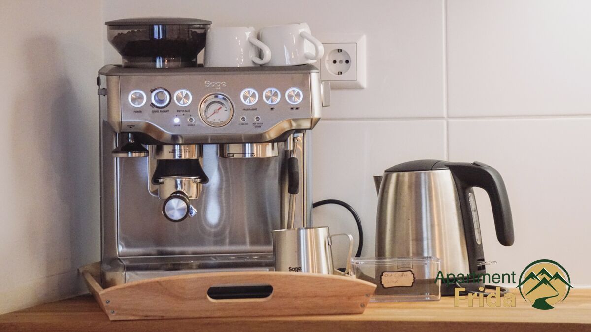 A coffee machine with a digital display, a water tank, and a coffee pot on a wooden tray.