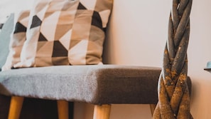 A close-up of a braided rope hanging from a chair with a grey upholstered seat and wooden legs. - Apartment Frida by Da Alois (Groebming)