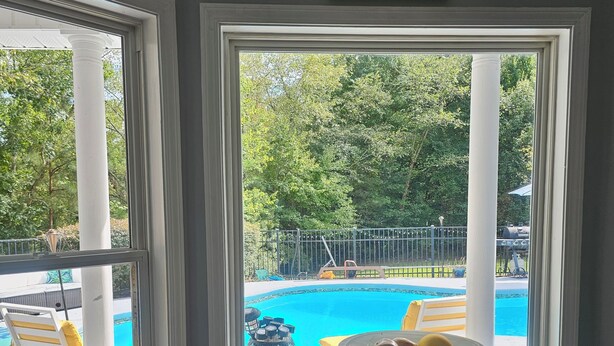 En matplats med utsikt över en swimmingpool, utemöbler och en dekorativ väggdekoration.