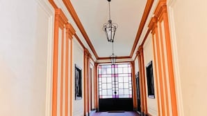 A long, narrow hallway with a patterned floor, wooden trim, and a hanging light fixture. - Piccole Suite di Charme (Turin)