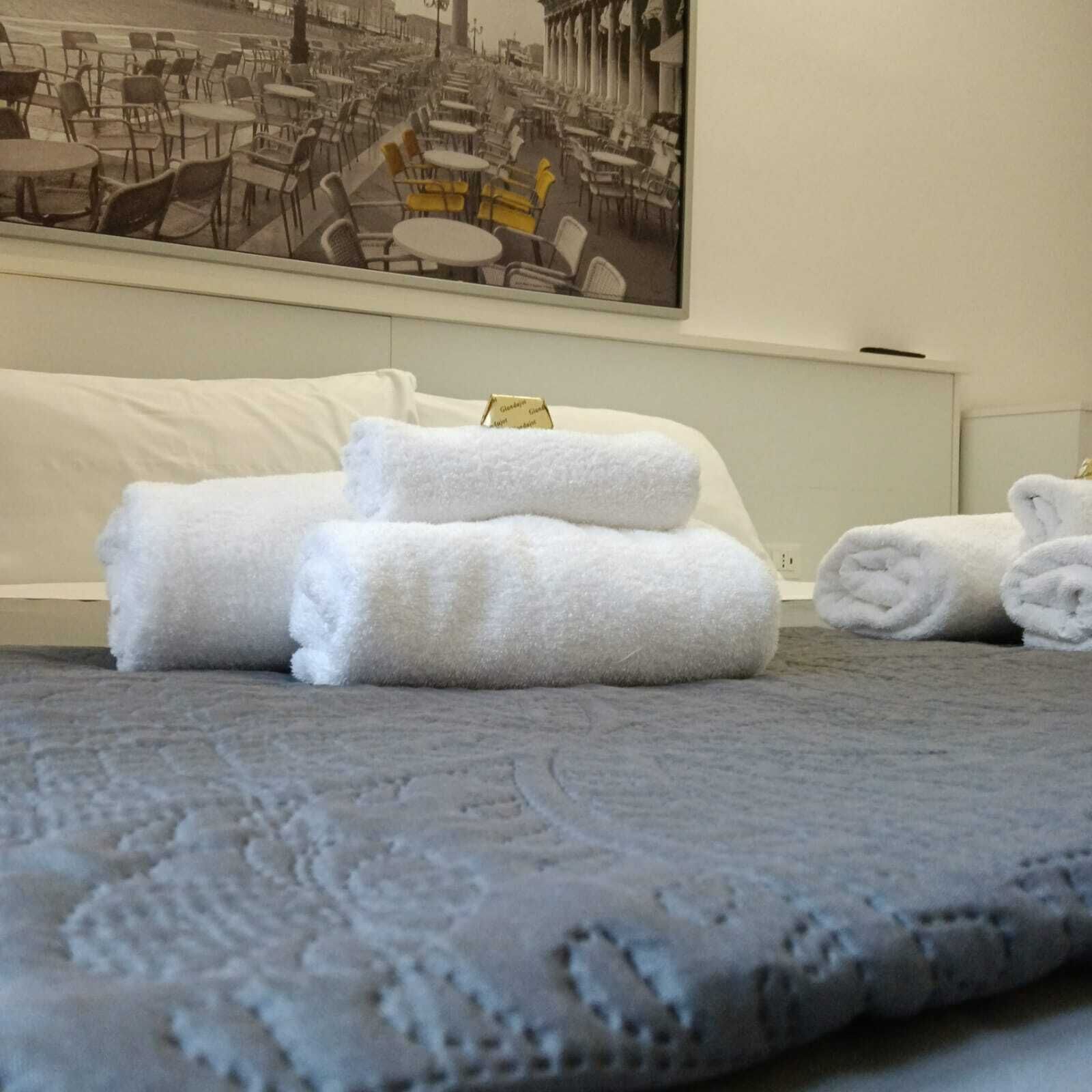 Ein Hotelzimmer mit einem Bett, einem grauen Teppich und einem Gemälde einer Straßencafé-Szene.