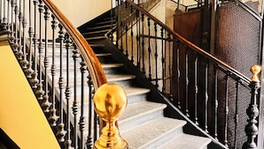 A staircase with a black metal railing and a golden balustrade. - Piccole Suite di Charme (Turin)