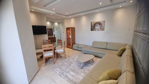 A modern living room with a sofa, a coffee table, and a TV mounted on the wall.