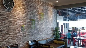 Un restaurant avec un mur en pierre, un espace pour s’asseoir et une horloge.