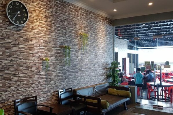 A restaurant with a stone wall, seating area, and a clock. - Pacific Inn, Semporna (Semporna)