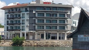 Un hotel de varios pisos con balcones, fachada de piedra y un cartel.