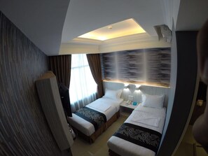 A hotel room with two beds, a large window with curtains, a wall-mounted air conditioning unit, and a ceiling light. - Pacific Inn (Semporna)