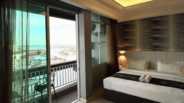 Une chambre d’hôtel avec un balcon, un lit et une vue sur la ville.
