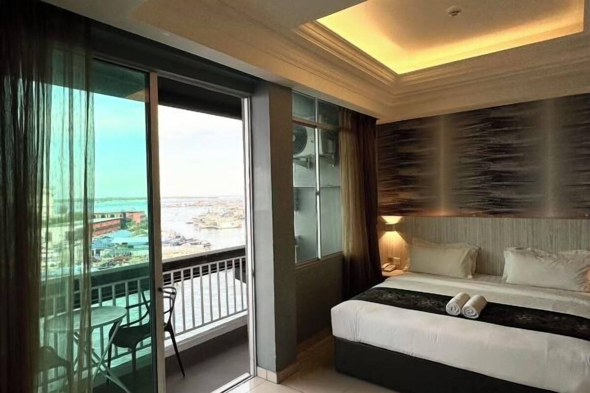 A hotel room with a balcony, a bed, and a view of the city.