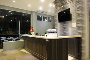 Una reception dal design moderno, una TV a schermo piatto a parete e un erogatore d'acqua.